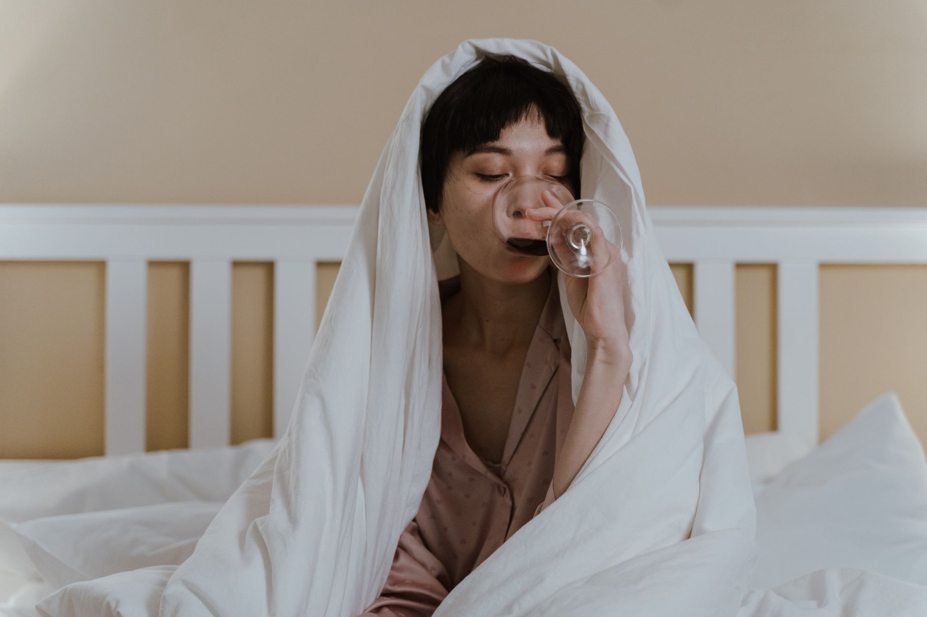 close up shot of a woman covered with white blanket drinking