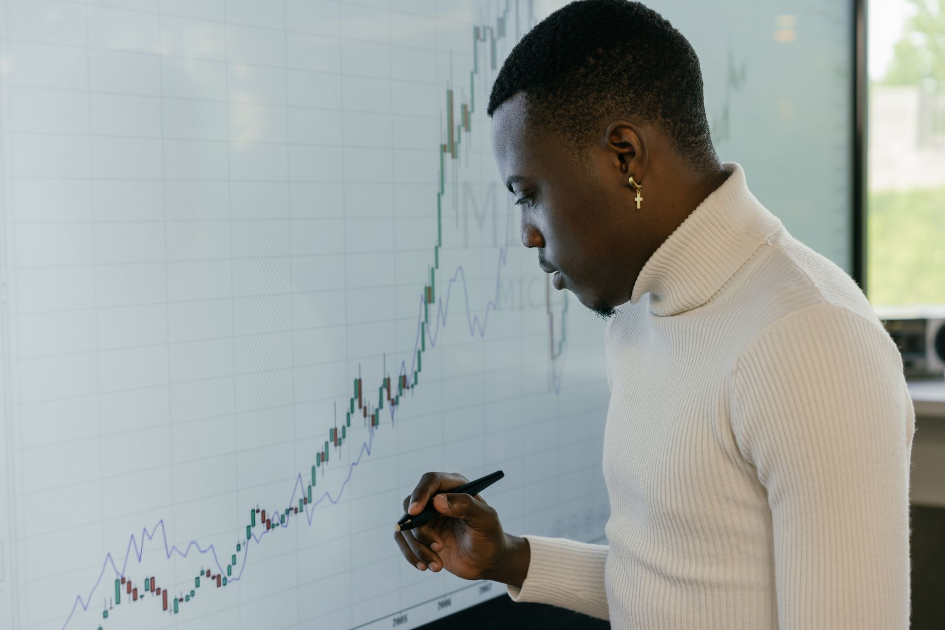 a man in a turtleneck sweater looking at a graph