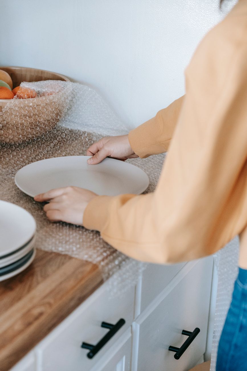 person packing a plate with bubble wrap