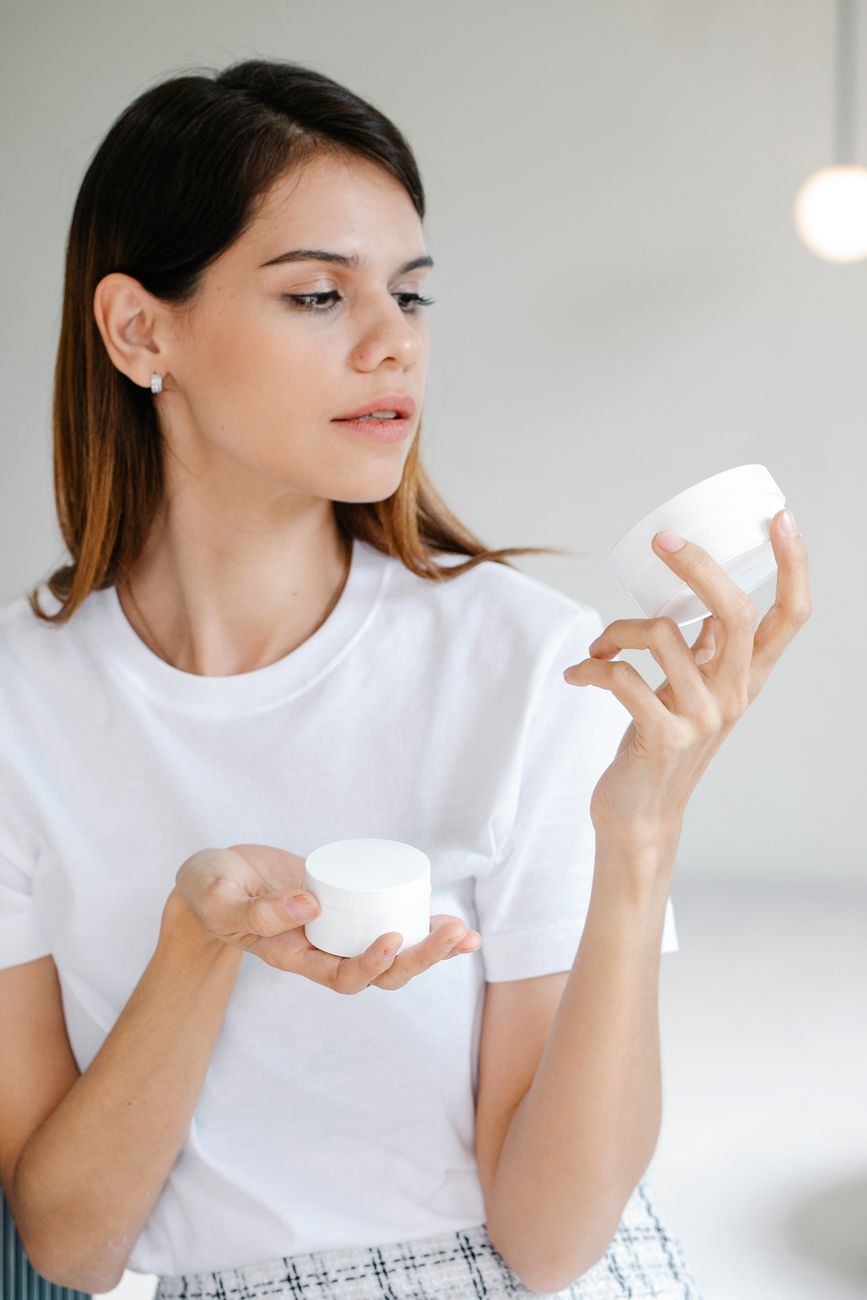 trendy young lady applying facial cream in studio