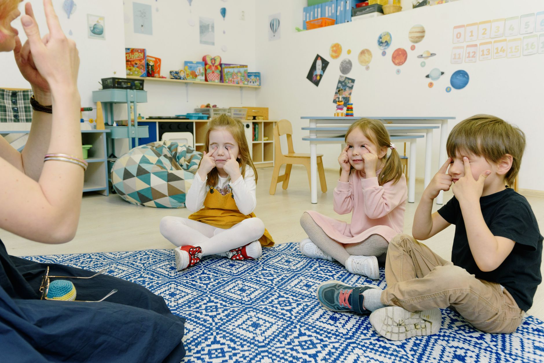 kids sitting on the floor and playing game with fingers on eyes