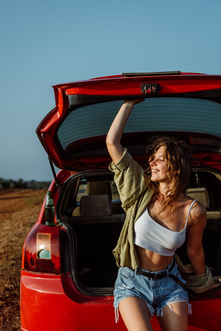 woman in white tank top and blue denim shorts sitting on car