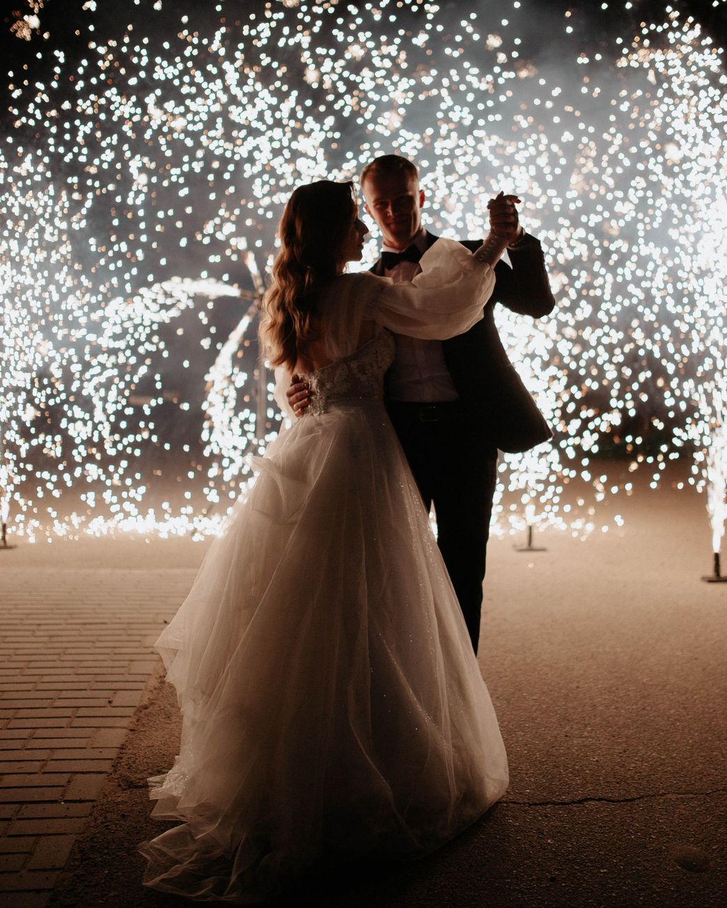 bride and groom dancing with fireworks in dark
