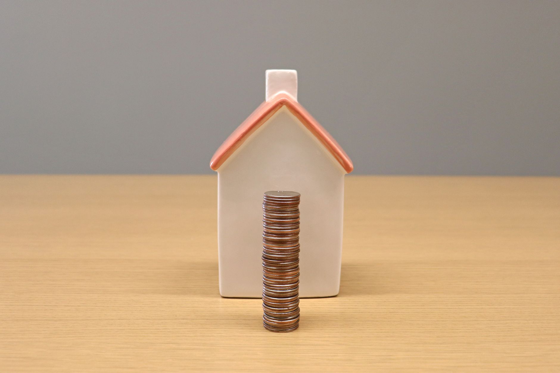 stack of coins in front of a porcelain house