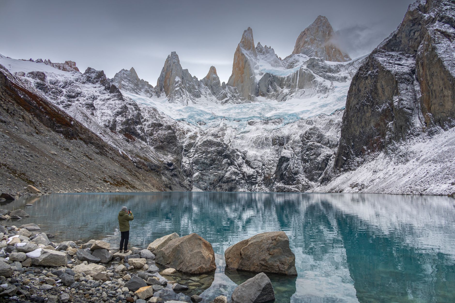 a man standing in front of a mountain lake