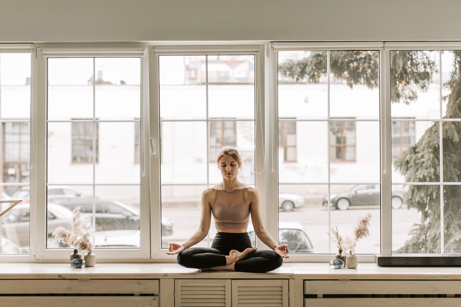 a woman sitting on a windowsill while meditating