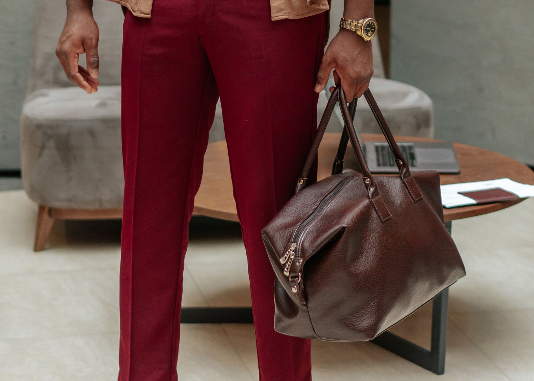person in red pants holding brown leather handbag