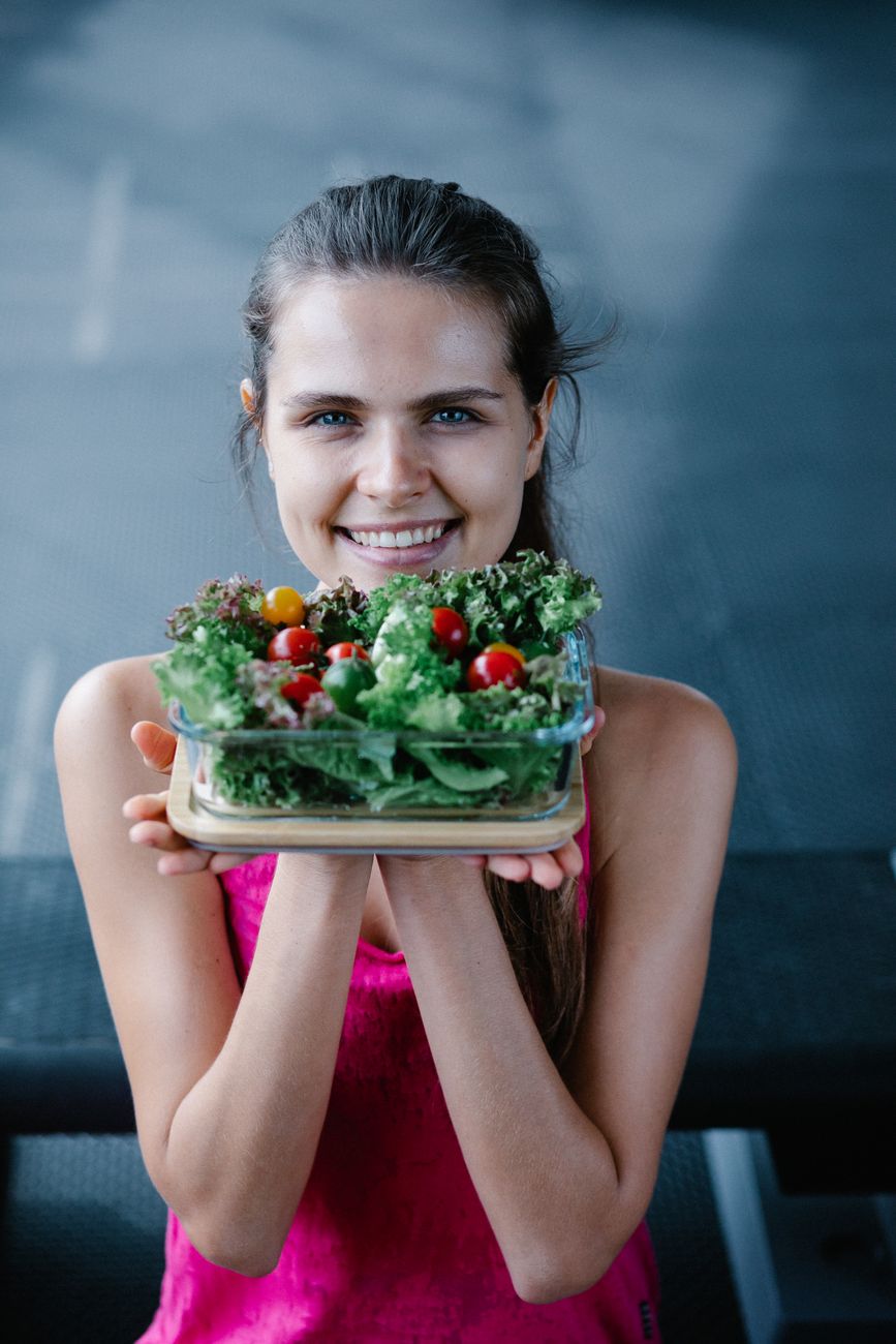 smiling woman holding a bowl with a salad