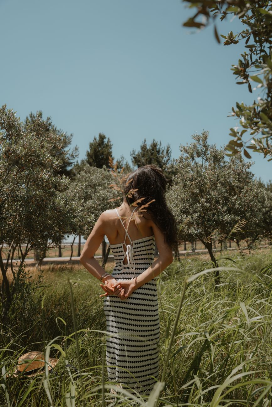 woman in summer dress amidst tall grass and trees
