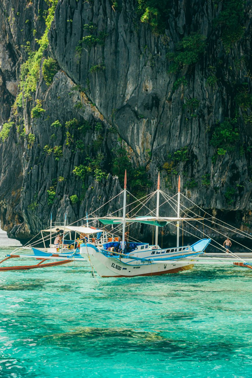 traditional boats by limestone cliffs in clear waters