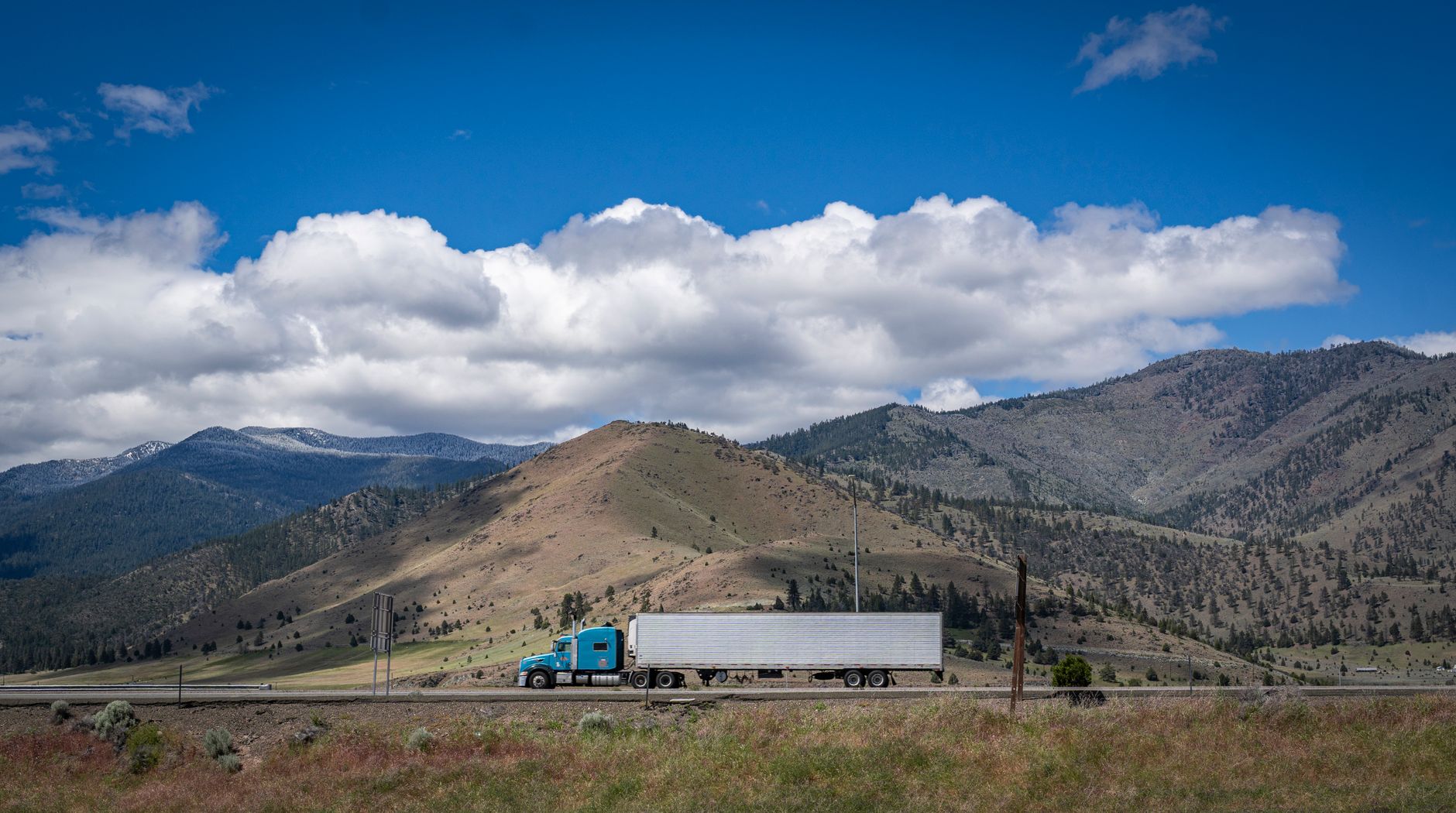 blue semi truck on a scenic mountain highway