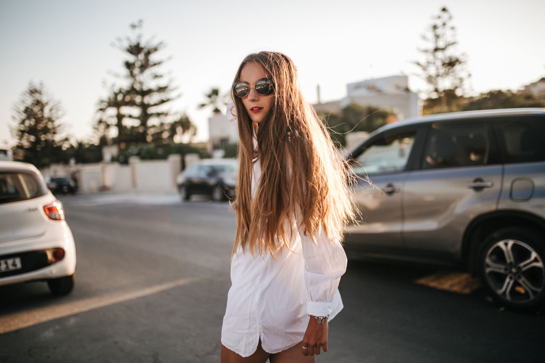 a long haired woman in white long sleeve dress standing on the road