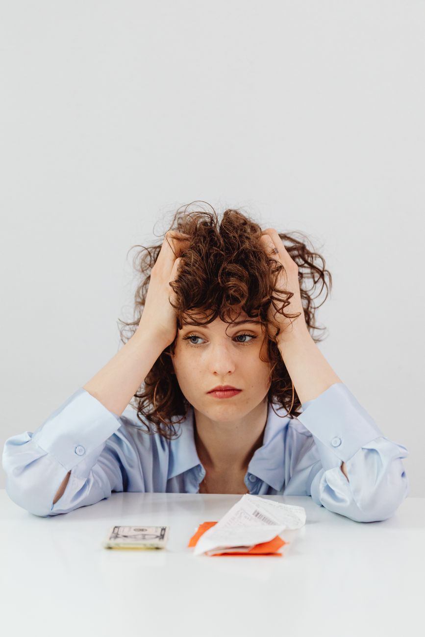 woman in blue long sleeve shirt holding her head