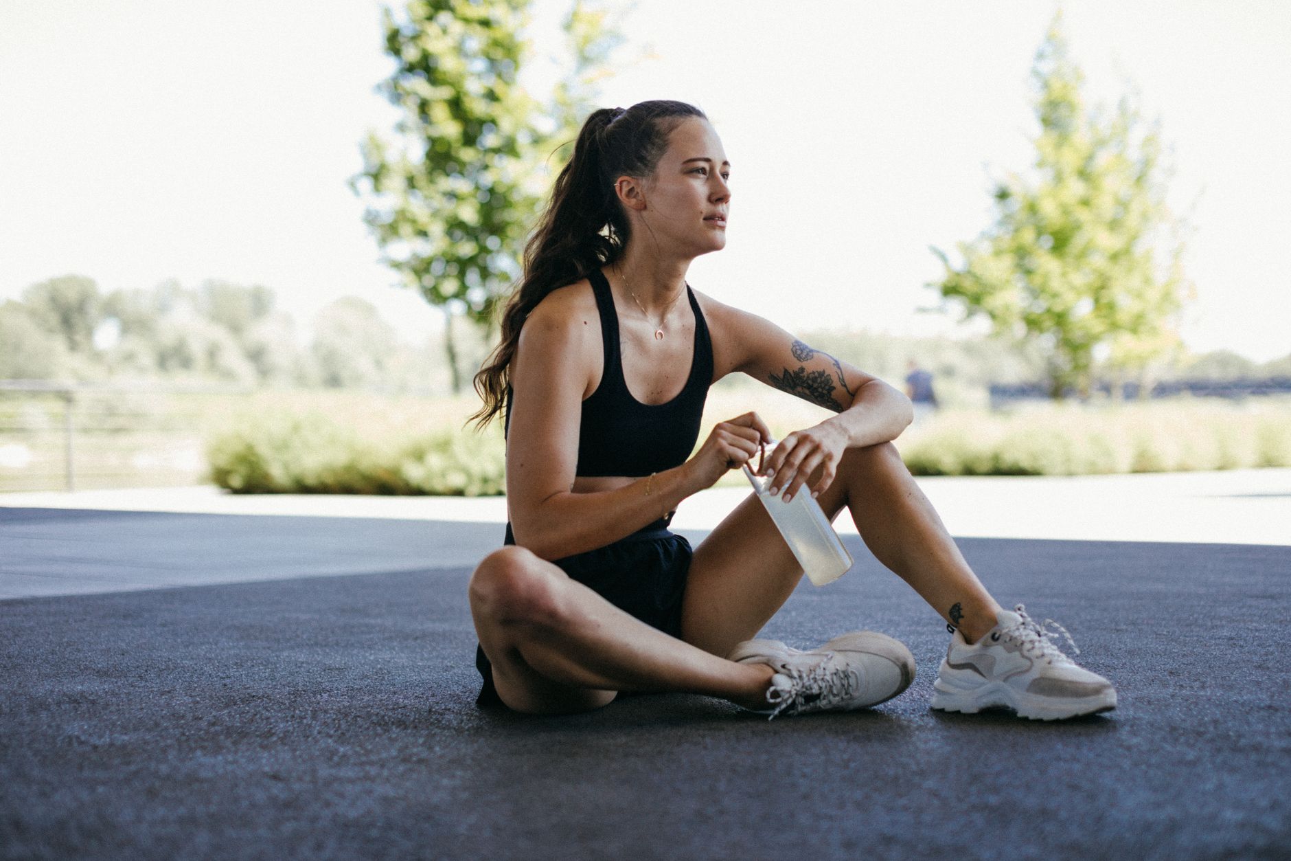 woman sitting on the ground holding her drink