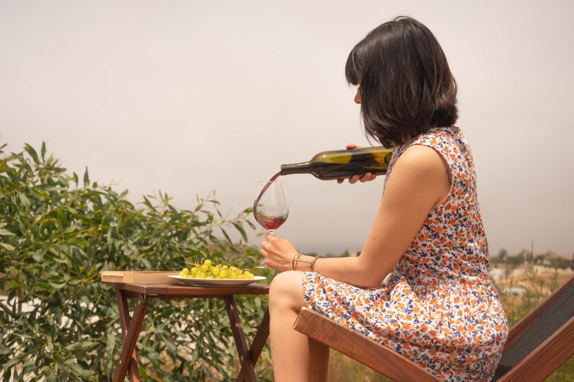 woman in floral dress pouring wine in wine glass
